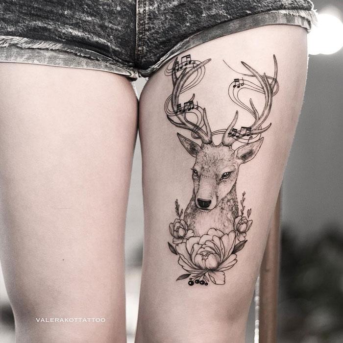 Женское тату на бедре в стиле графика, дотворк и випшейдинг. Татуировка олень, пионы и нотный стан для девушек