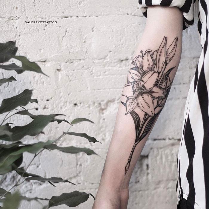 Женское тату на предплечье в стиле графика и гравюра. Татуировка с цветами лилии для девушек