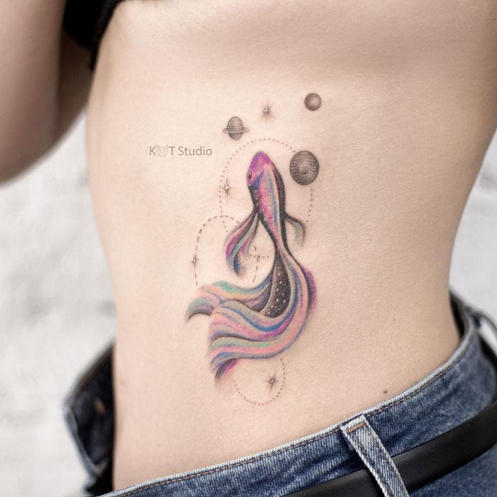 Женское цветное тату на боку с космосом и рыбой. Татуировка на ребрах для девушек знак зодиака рыбы