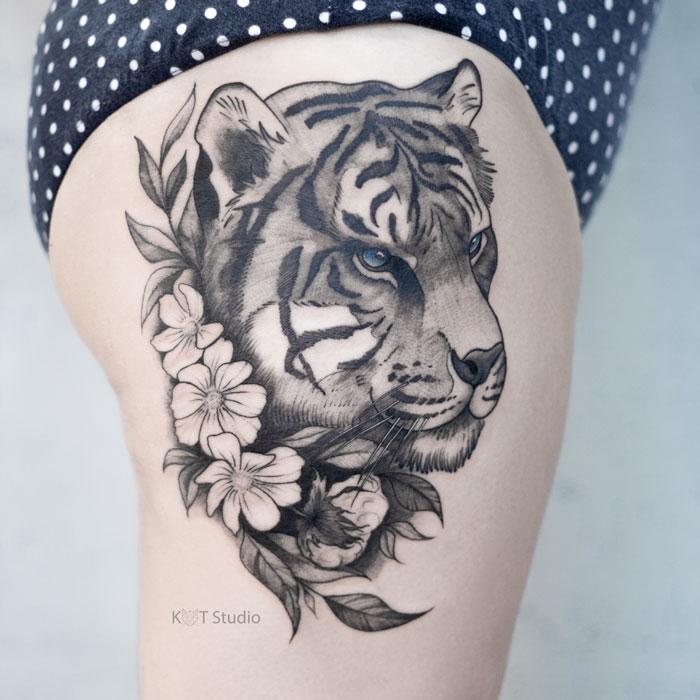 Женское тату на бедре в стиле графика с животными. Татуировка тигра с цветами на ноге